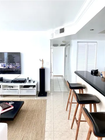 a kitchen with stainless steel appliances kitchen island granite countertop a dining table chairs and a refrigerator