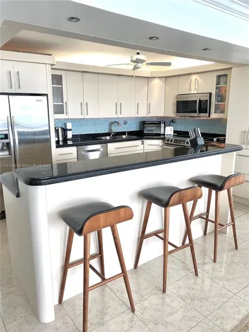 a kitchen with stainless steel appliances granite countertop table chairs sink and cabinets