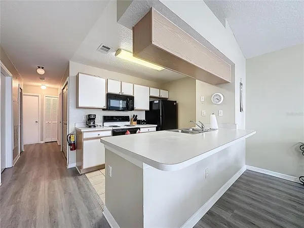 a large white kitchen with kitchen island a stove a sink a refrigerator and a microwave