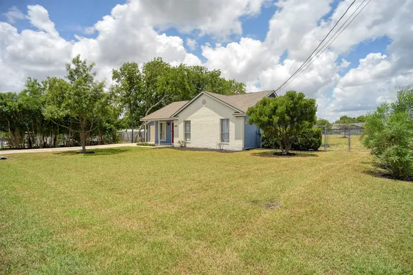 a front view of house with yard and trees in the background