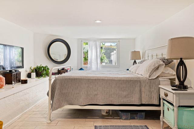 a bed sitting in a bedroom next to a window with a bookshelf
