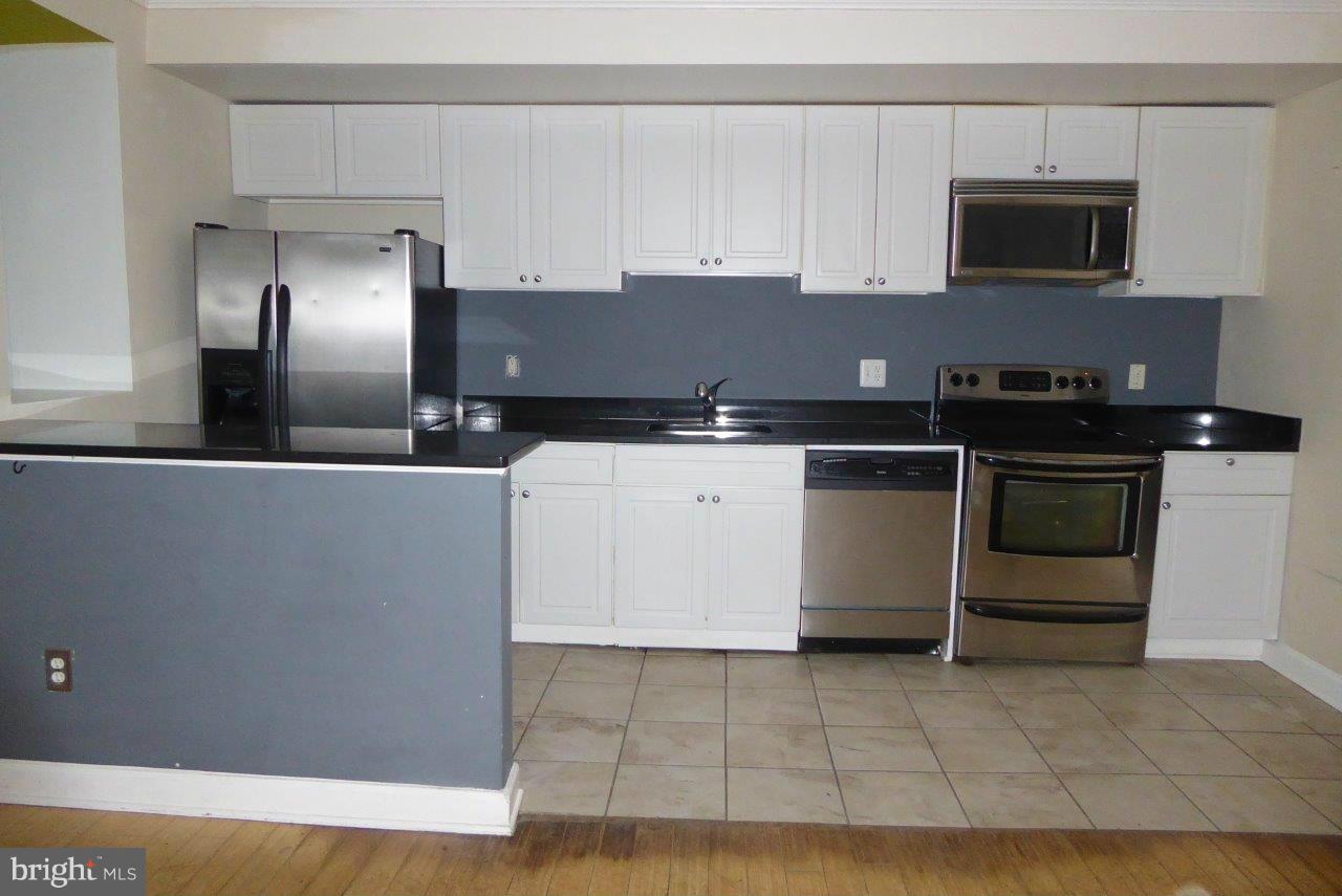 1246 Queen Street Northeast, Unit 3 Washington, DC 20002 - Photo 13 of 14 a kitchen with granite countertop a stove a microwave a sink and cabinets