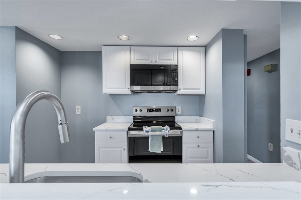 165 Cottage Street, Unit 711 Chelsea, MA 02150 - Photo 7 of 39 a kitchen with stainless steel appliances granite countertop a stove a sink and a microwave