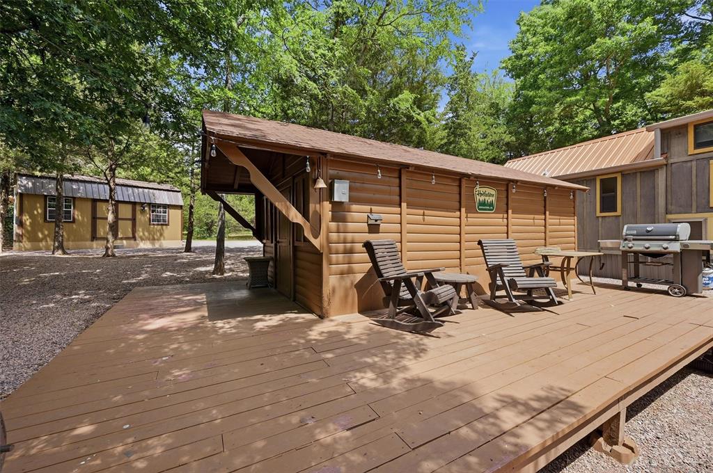 3958 Ranch Road Whitesboro, TX 76273 - Photo 25 of 40 Wood-finish deck with a detached wood-sided structure featuring an extended overhang, shingle roof, and exterior lighting