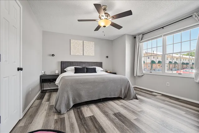 a bedroom with a bed and a large window with wooden floor