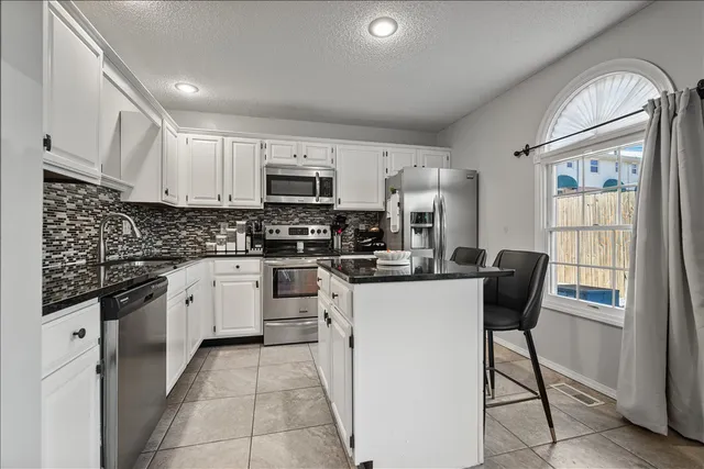 a kitchen with stainless steel appliances granite countertop a refrigerator sink stove microwave and cabinets