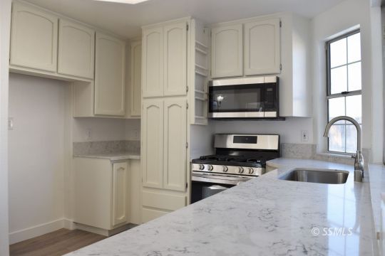 1132 West Robert Avenue Ridgecrest, CA 93555 - Photo 12 of 38 a kitchen with granite countertop a stove a sink and a microwave