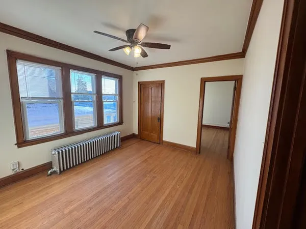 an empty room with wooden floor fan and windows