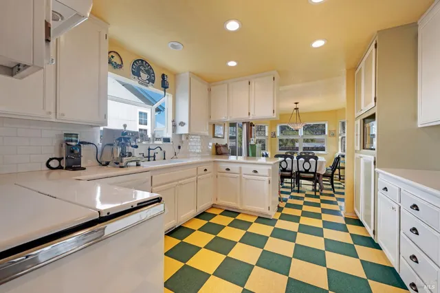 a kitchen with a sink a stove and white cabinets