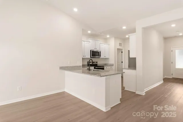 a view of kitchen with stainless steel appliances refrigerator stove microwave and cabinets