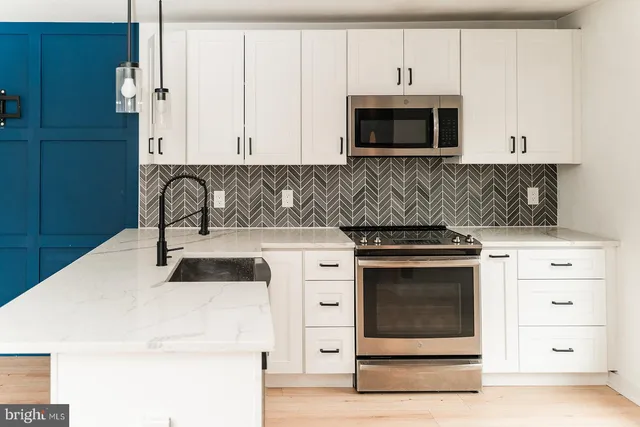 a kitchen with granite countertop white cabinets and stainless steel appliances