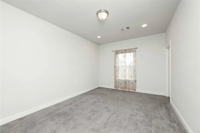 an empty room with a window and ceiling fan