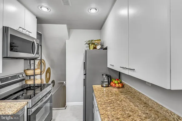 a kitchen with granite countertop white cabinets and stainless steel appliances