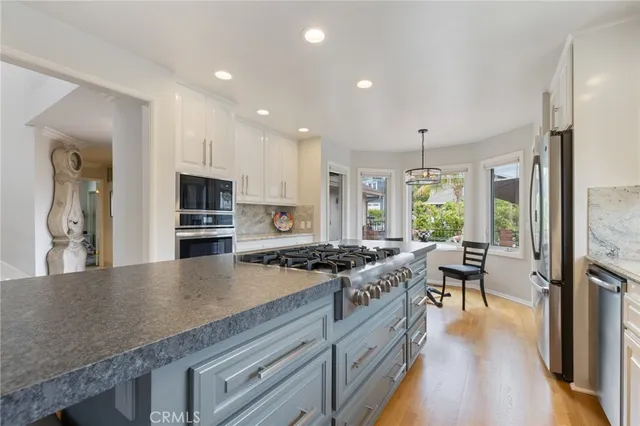 a kitchen with stainless steel appliances granite countertop a stove oven and a refrigerator with white cabinets