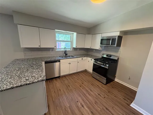 a kitchen with stainless steel appliances granite countertop a sink a stove top oven a counter space and cabinets