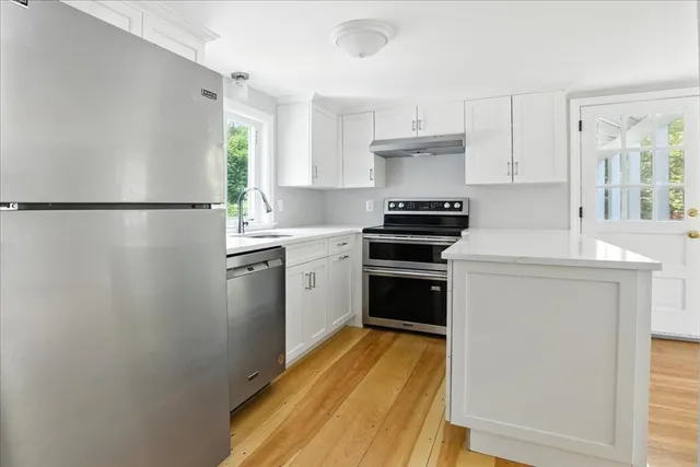 a kitchen with a refrigerator and white cabinets