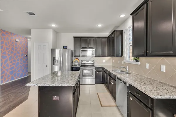 a kitchen with stainless steel appliances granite countertop a sink stove and refrigerator