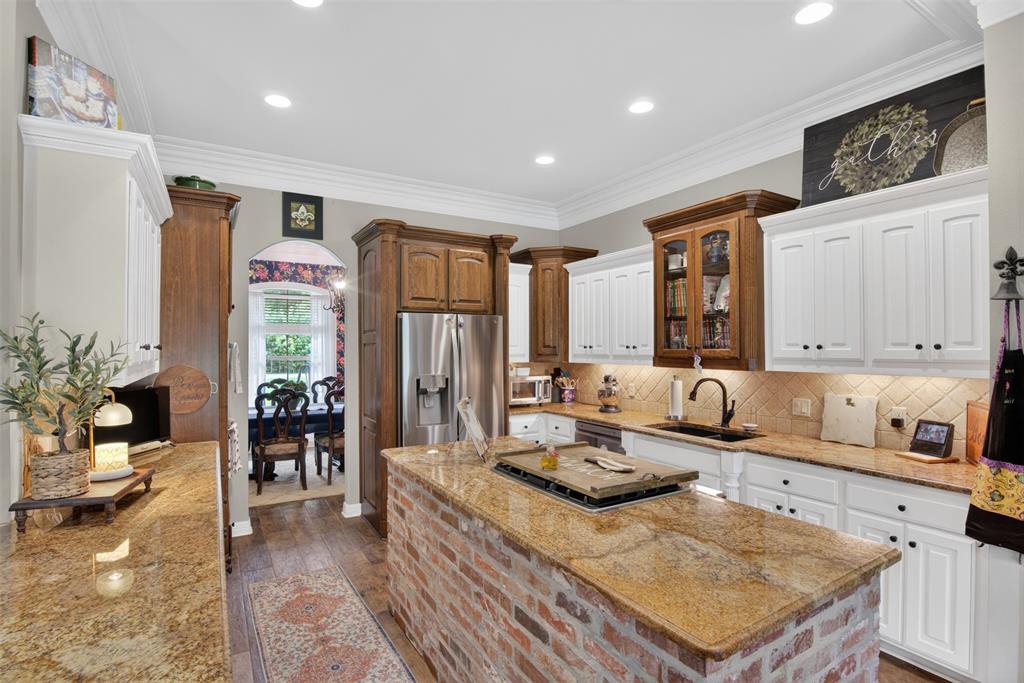 11868 Timber Ridge Drive Keithville, LA 71047 - Photo 10 of 37 Spacious kitchen featuring a brick-clad island with granite countertop, stainless steel appliances, white cabinetry with dark hardware, and recessed lighting