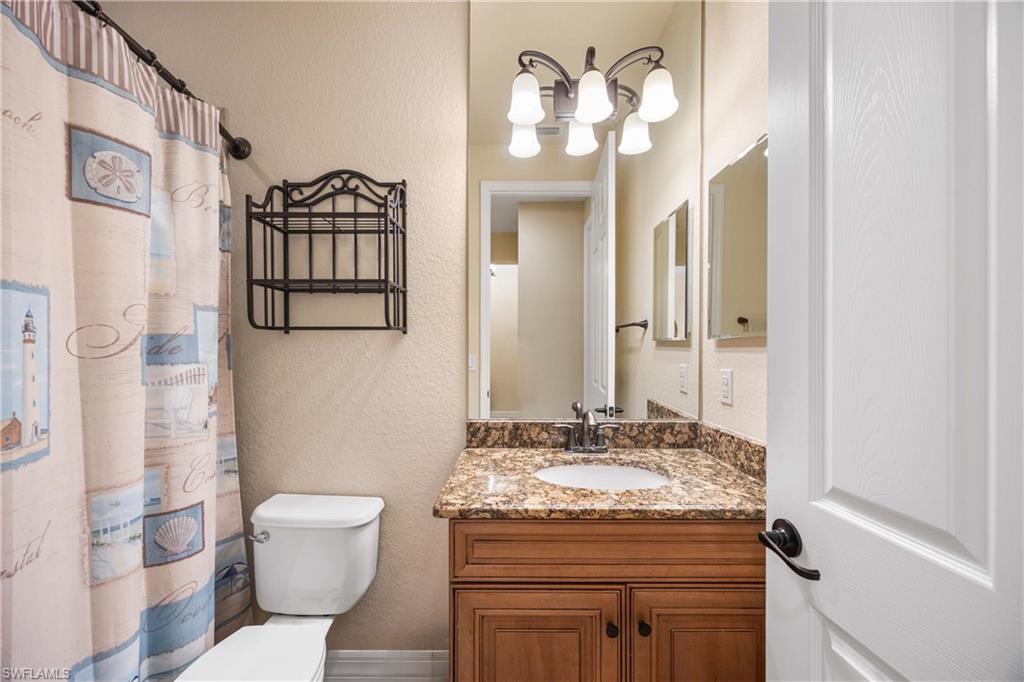 9234 Veneto Place Naples, FL 34113 - Photo 24 of 38 a bathroom with a granite countertop sink a toilet and a mirror