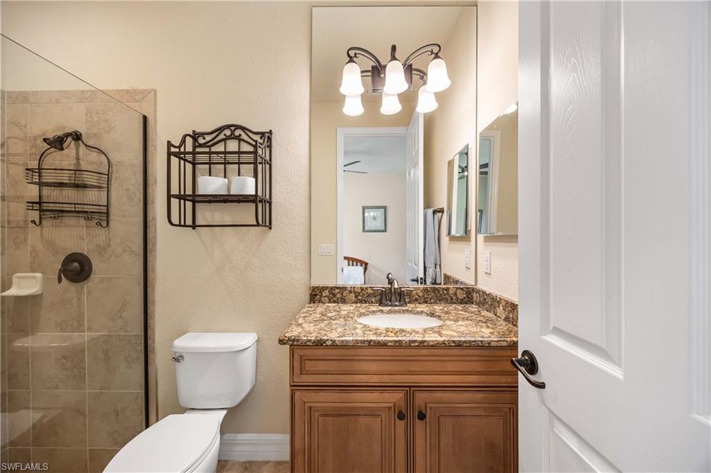 9234 Veneto Place Naples, FL 34113 - Photo 26 of 38 a bathroom with a granite countertop sink toilet and shower