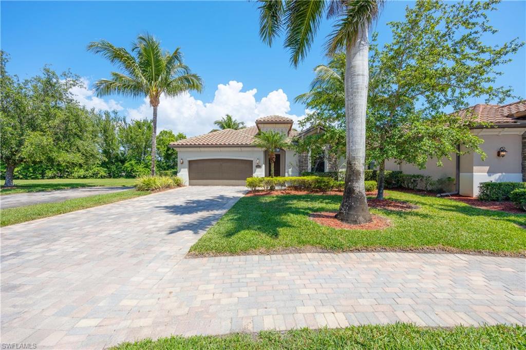9234 Veneto Place Naples, FL 34113 - Photo 33 of 38 a front view of a house with a yard and palm trees
