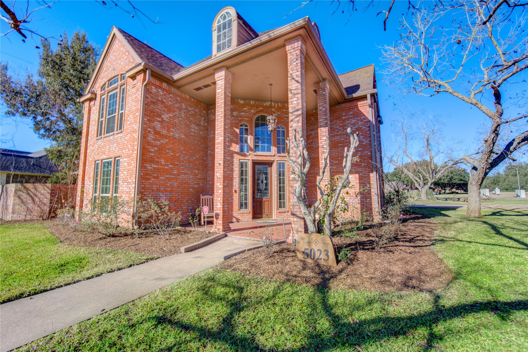 a view of a house with brick walls and a yard with plants