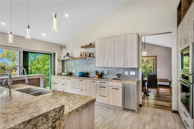 a kitchen with a stove a sink a counter top space and living room view