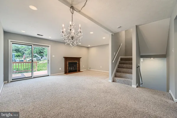 a view of an empty room with fireplace stairs and windows