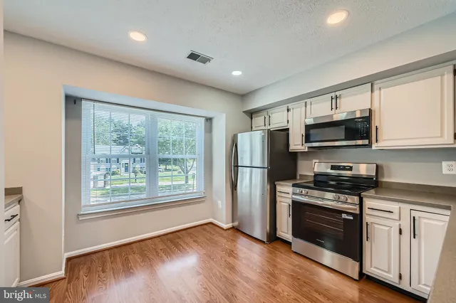 a kitchen with stainless steel appliances wooden floors and wooden cabinets