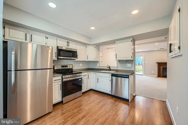 a kitchen with a refrigerator a stove top oven a sink and dishwasher with wooden floor