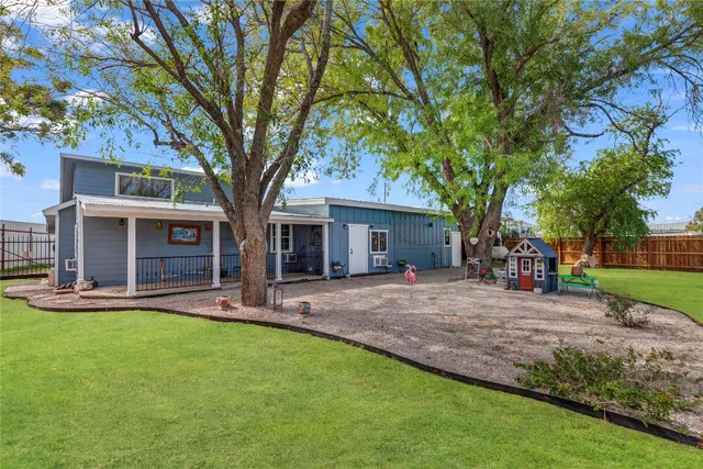 a view of a house with a yard and large tree