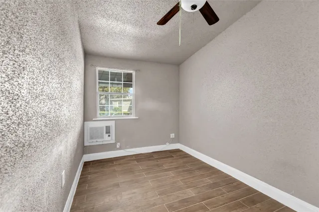 an empty room with wooden floor fan and windows