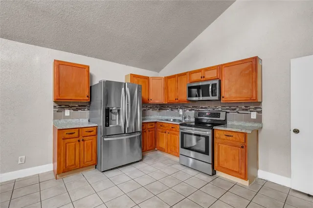 a kitchen with white cabinets a refrigerator and a stove top oven