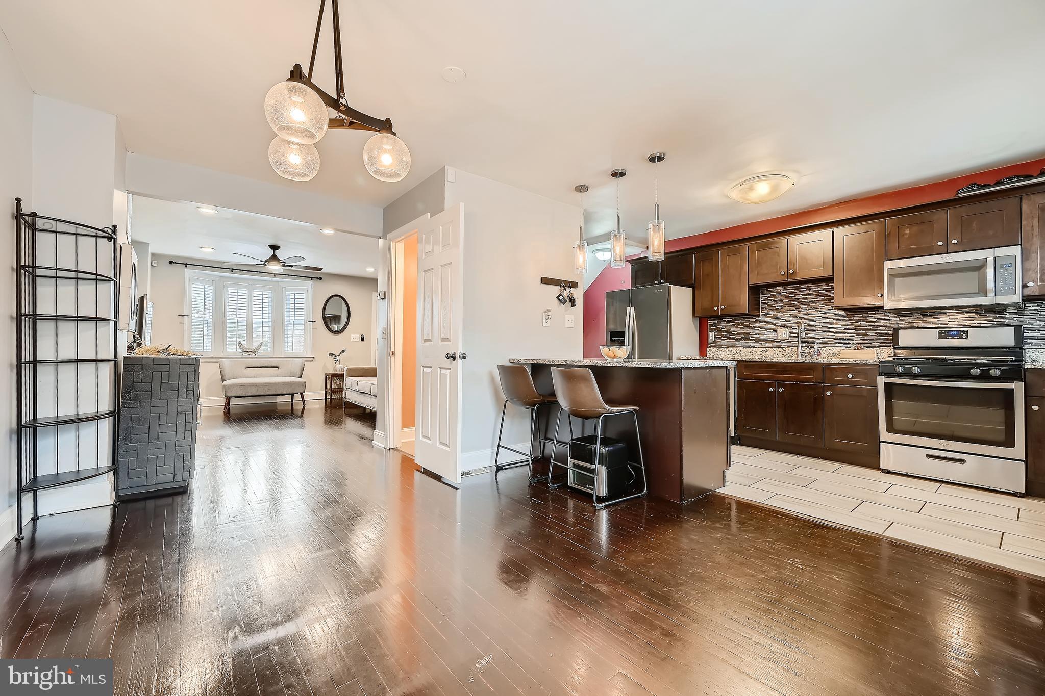 3828 Ednor Road Baltimore, MD 21218 - Photo 9 of 27 a kitchen with stainless steel appliances kitchen island granite countertop a stove top oven a sink a dining table and chairs with wooden floor