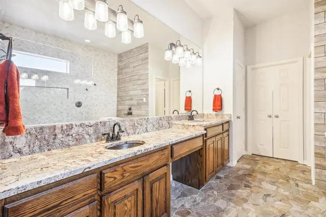 a bathroom with a granite countertop double vanity sink and a mirror