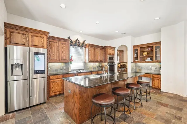 a kitchen with stainless steel appliances granite countertop a sink and a refrigerator