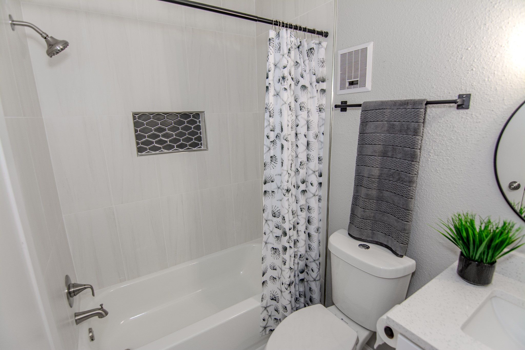13009 Wirevine Lane Houston, TX 77072 - Photo 14 of 18 Spa like bathroom features a sleek design with a white bathtub and shower combo, accented by a modern tile backsplash. It includes a contemporary vanity, toilet, and towel rack.