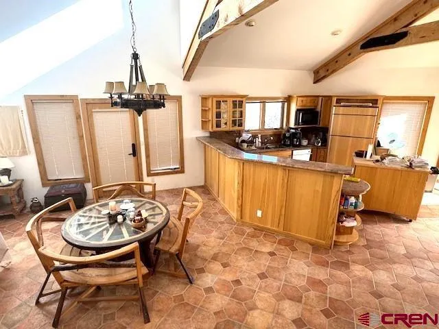 a kitchen with stainless steel appliances granite countertop a stove top oven a sink a dining table and chairs