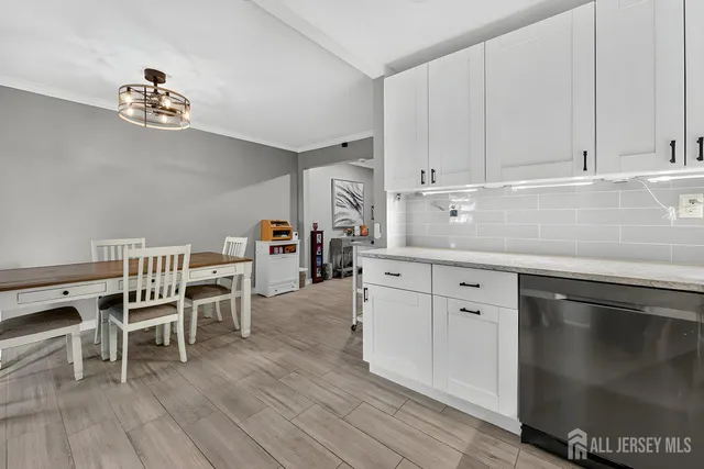 a kitchen with stainless steel appliances granite countertop a dishwasher a stove a dining table and chairs with wooden floor