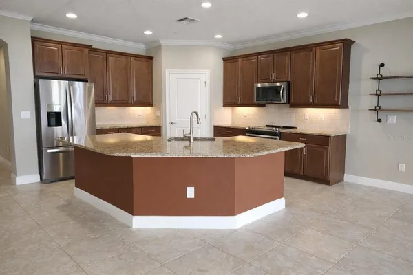 a kitchen with granite countertop a table chairs microwave and cabinets
