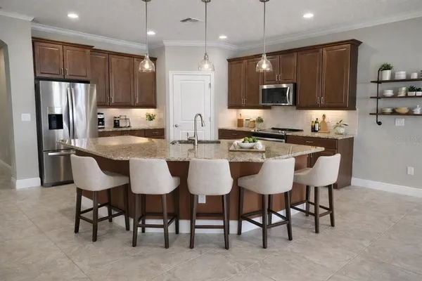 a large kitchen with kitchen island a large counter top stainless steel appliances and cabinets