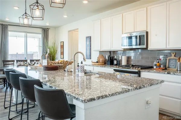 a kitchen with kitchen island granite countertop a table chairs sink and cabinets