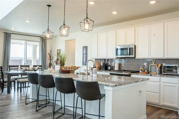 a kitchen with stainless steel appliances granite countertop a stove a sink dishwasher a dining table and chairs with wooden floor