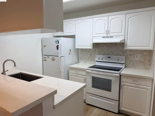 a kitchen with white cabinets and white appliances