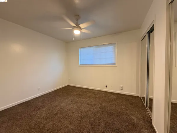 an empty room with a window and a fan