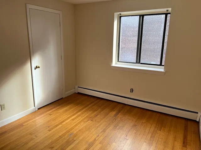 a view of an empty room with window and wooden floor