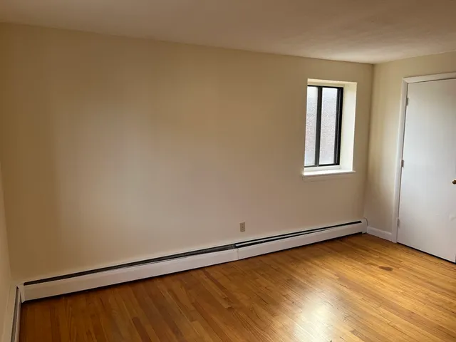 a view of a room with wooden floor and a window