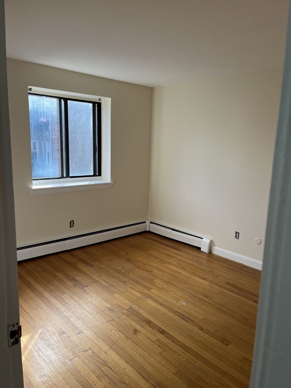 39 Linden Street, Unit 21 Boston, MA 02134 - Photo 17 of 20 a view of an empty room with window and wooden floor