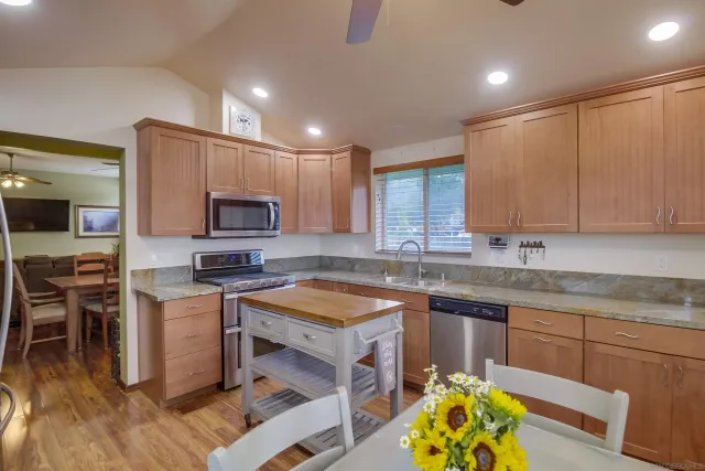 a kitchen with a stove a sink a dining table and chairs with wooden floor
