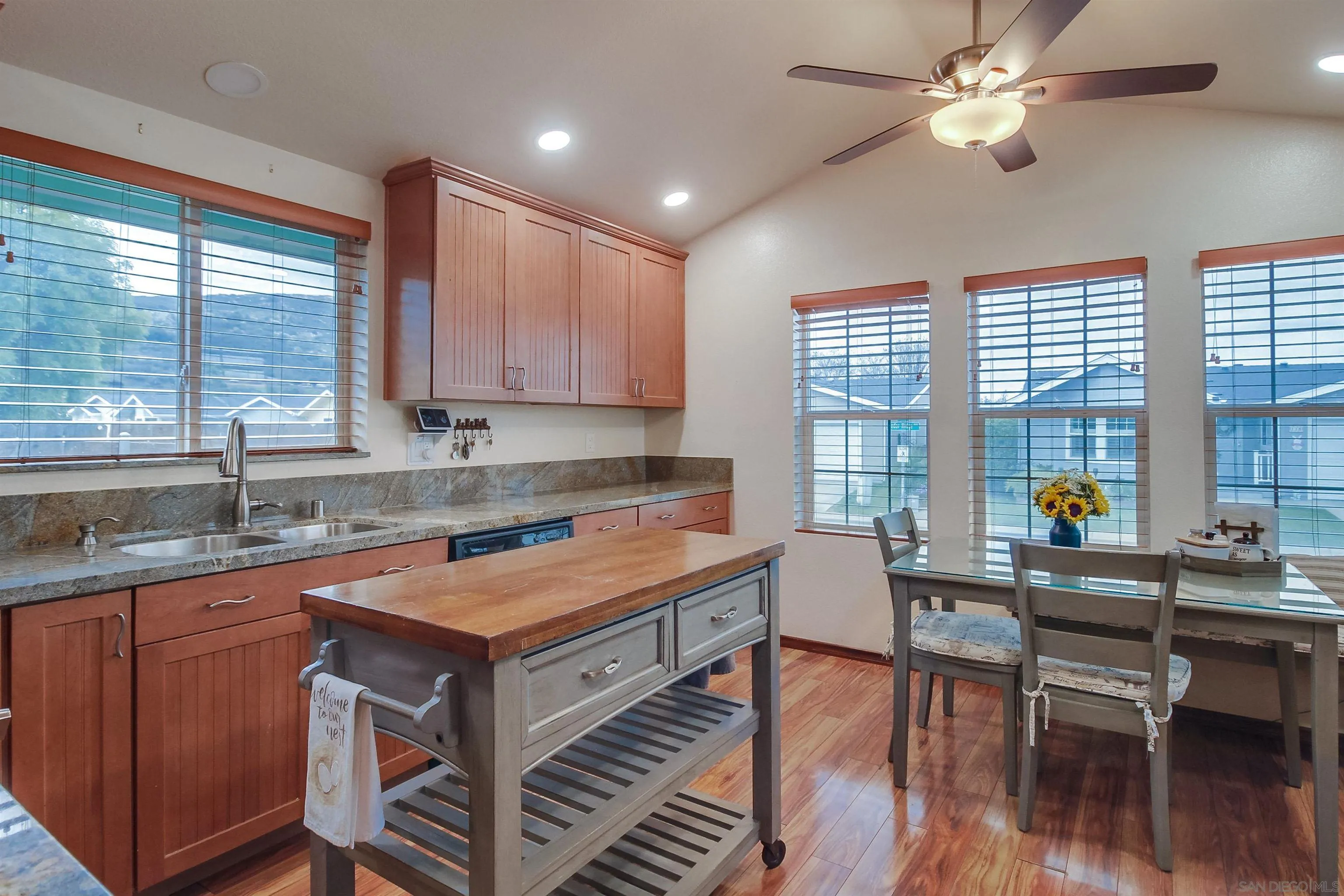 15935 Spring Oaks Road El Cajon, CA 92021 - Photo 24 of 66 a kitchen with a stove a sink a dining table and chairs with wooden floor
